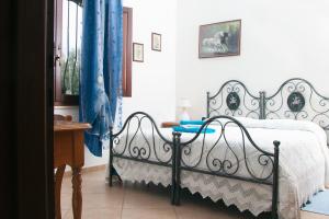 um quarto com uma cama em preto e branco com cortinas azuis em Il Vecchioliveto di Ornella em Marrùbiu