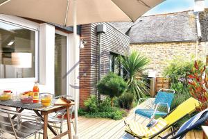 a patio with a table and chairs and an umbrella at LocaLise - M20 - La maison des Dunes à 2 pas du centre - Tout à pied, plage, port, centre, commerces marché - Wifi inclus - Linge de lit inclus - Animaux bienvenus in Le Guilvinec