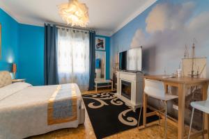 ein blaues Schlafzimmer mit einem Bett, einem Schreibtisch und einem TV in der Unterkunft Pisa Happy House in Pisa
