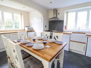 una cucina con tavolo in legno, piatti e bicchieri da vino di Minffordd a Llangollen