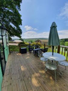 a deck with a table and chairs and an umbrella at Howgill farm Bolton Abbey in Appletreewick