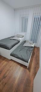 two beds in a bedroom with a wooden floor at Street C apartment nr 2 in Pristina