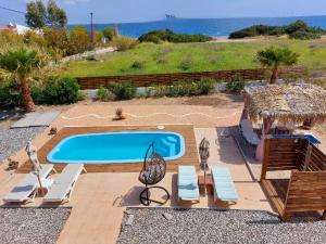 einen Pool mit Stühlen, einem Tisch und dem Meer in der Unterkunft Gennadi Serenity House- beachfront villa with pool in Gennadi