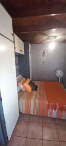 a small bedroom with a bed with orange sheets at Anchor Aweigh Chalet 86 in Hibberdene