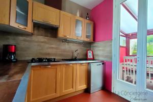 a kitchen with wooden cabinets and pink walls at AL 11 - Villa "La Lisette" 8 personnes in Ault