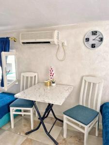 uma mesa e cadeiras num quarto com um relógio na parede em Savić Apartments em Kotor