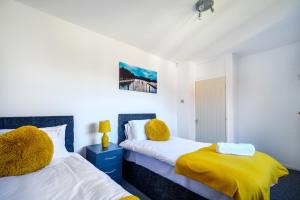 a bedroom with two beds and a yellow blanket at Starview Apartment-Manchester Airport in Manchester