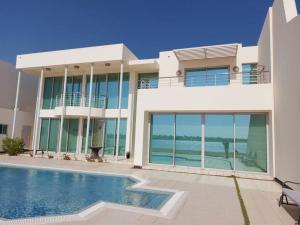 a house with a swimming pool in front of it at Family friendly house in Bahrian in Durrat Al Bahrain