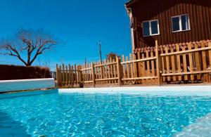 a house with a wooden fence and a swimming pool at The Farm in Bouglon