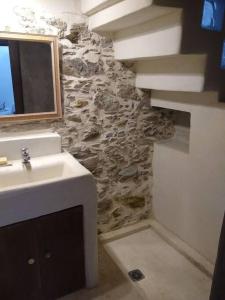 uma casa de banho com um lavatório e uma parede de pedra em The Village House em Kerames