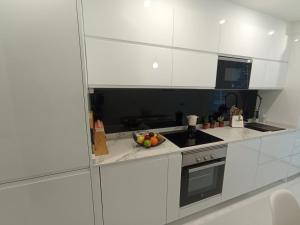 una cocina con armarios blancos y un bol de fruta en la barra en Súper apartamento Santiago en Santiago de Compostela