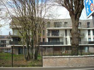 un bâtiment avec une clôture et des arbres devant lui dans l'établissement Chalet appartement, à Lille