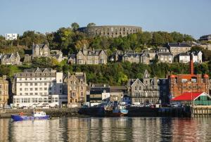 a city with houses and boats in the water at Strathisla Garden Apartment, Oban in Oban