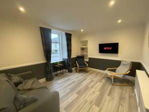 a living room with a couch and chairs and a tv at Strathisla Garden Apartment, Oban in Oban