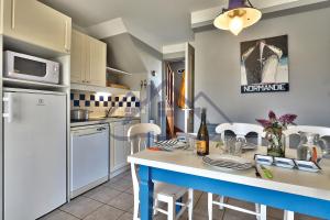 eine Küche mit weißen Geräten und einem Tisch mit Stühlen in der Unterkunft LocaLise - Maison E2 au Guilvinec - A 20m de la mer avec jardin et piscine - Tout à pied, plage, port, centre commerces, marché - Wifi inclus - Vue mer de la chambre - Animaux bienvenus - Linge de lit inclus in Le Guilvinec