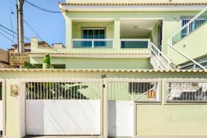 una casa verde con una puerta de garaje blanca en Suíte para solteiro em ambiente familiar, en Río de Janeiro