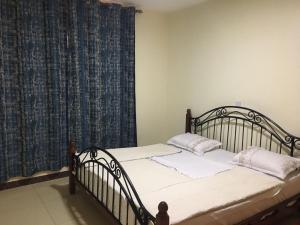 Schlafzimmer mit einem Bett und einem Fenster mit Vorhängen in der Unterkunft JM Apartment in Kigali