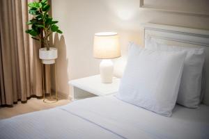 Cama con almohada blanca y mesa con lámpara en Apartament Zafi Lakeview en Constanza