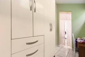 un armario blanco con mangos de plata en una habitación en Quarto com banheiro para solteiros no Rio de Janeiro en Río de Janeiro
