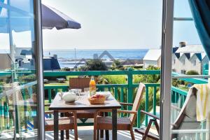 una mesa en un balcón con vistas al océano en LocaLise au Guilvinec - A28 - Belle vue sur la mer, la piscine et le jardin - - Tout à pied, plages, port, centre, commerces, marché - Wifi inclus - Linge de lit inclus en Le Guilvinec