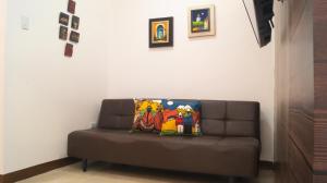 Sofá marrón en una habitación con pared blanca en Remodeled Downtown Apartment - Centro de Guayaquil, en Guayaquil