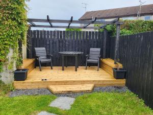 a wooden deck with chairs and a table in a backyard at Kesh self catering holiday home. in Kesh