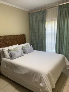 a bedroom with a large white bed and a window at Tshamani self catering in Hazyview