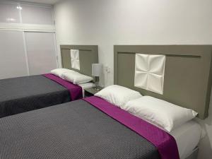 2 camas en una habitación de color púrpura y blanco en Posada 53 en Mazatlán