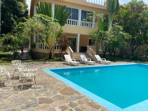 een villa met een zwembad en stoelen en een huis bij 4 bedroom villa, security, private pool, ocean view in Sosúa