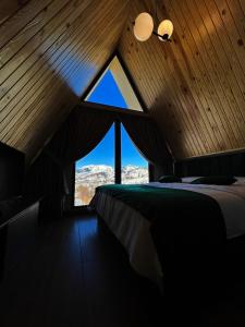 a bedroom with a bed and a large window at CABANA 7 CRESTE in Borşa