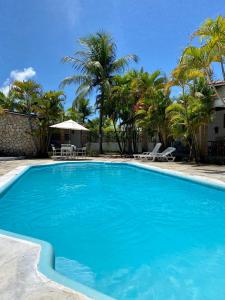 a swimming pool with blue water and palm trees at Village do Sossego in São José da Coroa Grande +20 photos