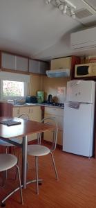 eine Küche mit einem Tisch und einem weißen Kühlschrank in der Unterkunft CAMPING LE BEL AIR mobil home LE FIGUIER 6 personnes in Limogne-en-Quercy