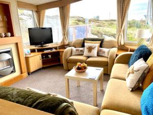 ein Wohnzimmer mit 2 Sofas und einem TV in der Unterkunft Earls View Caravan in Carna