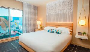 a bedroom with a white bed and a large window at Kimpton Hotel Wilshire by IHG in Los Angeles