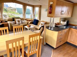 eine Küche und ein Wohnzimmer mit einem Tisch und einem Sofa in der Unterkunft Earls View Caravan in Carna