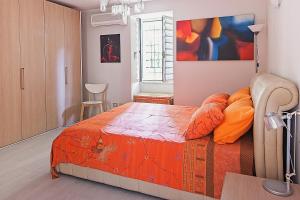 a bedroom with a bed with orange pillows and a painting at Pavillon d'Angleterre au cœur de la ville in Menton