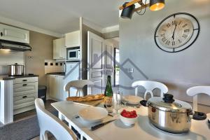 a kitchen with a table with a clock on the wall at LocaLise au Guilvinec - A16 - Vue sur la mer, la piscine et le jardin - Tout à pied, plages, port, centre, commerces, marché - Wifi inclus - Animaux bienvenus - Linge de lit inclus in Le Guilvinec