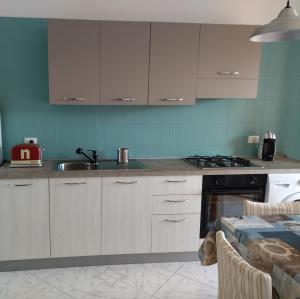 Una cocina con gabinetes blancos, un fregadero y una estufa. en La Casa degli Artisti 2, en Realmonte