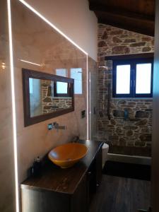 Casa Romantica في Petriaí: حمام مع حوض خشبي وجدار حجري