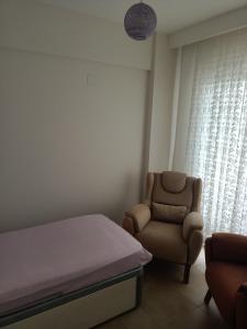 ein Schlafzimmer mit einem Bett und einem Stuhl in der Unterkunft QUEENABA SiTESi in Erdemli
