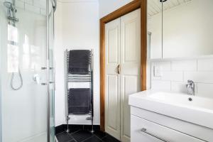 a white bathroom with a sink and a shower at The Pool House - King Deluxe Studio in Motueka