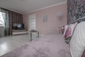 ein Wohnzimmer mit einem Bett und einem TV in der Unterkunft LULU APARTAMENT in Ventspils