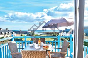 a table on a balcony with a view of the ocean at LocaLise au Guilvinec - A22 - Belle vue sur la mer, la piscine et le jardin - Tout à pied, plages, port, centre, commerces, marché - Wifi inclus - Animaux bienvenus - Linge de lit inclus in Le Guilvinec
