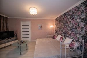 Schlafzimmer mit einem Bett, einem TV und einer Blumenwand in der Unterkunft LULU APARTAMENT in Ventspils