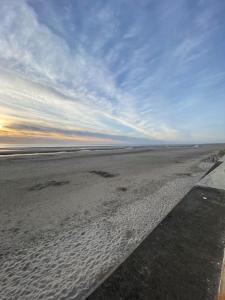 una playa con un cielo nublado y huellas en la arena en Les Familles à la mer, en Merlimont
