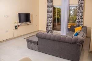 ein Wohnzimmer mit einem Sofa und einem TV in der Unterkunft A Cozy 3 Bed Apartment With a Swimming Pool in Nyali - Beach Front in Mombasa