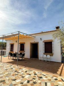 ein weißes Haus mit einer Terrasse mit Tischen und Stühlen in der Unterkunft Casa rural Río Grande, Coín in Coín