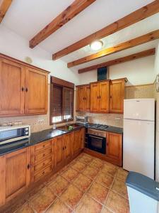 uma cozinha com armários de madeira e um frigorífico branco em Casa rural Río Grande, Coín em Coín