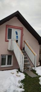 una casa con una puerta y escaleras en la nieve en Guesthouse Sjenicic, en Guča