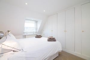 een witte slaapkamer met witte kasten en een bed bij Contemporary 1 Bed Flat in Fulham Near The Thames in Londen